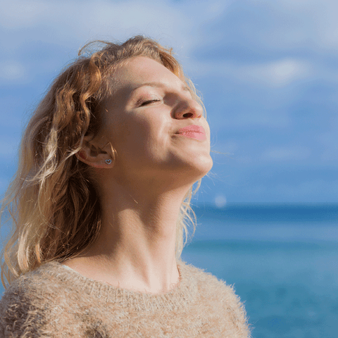 Woman outside smiling up at the sunny sky